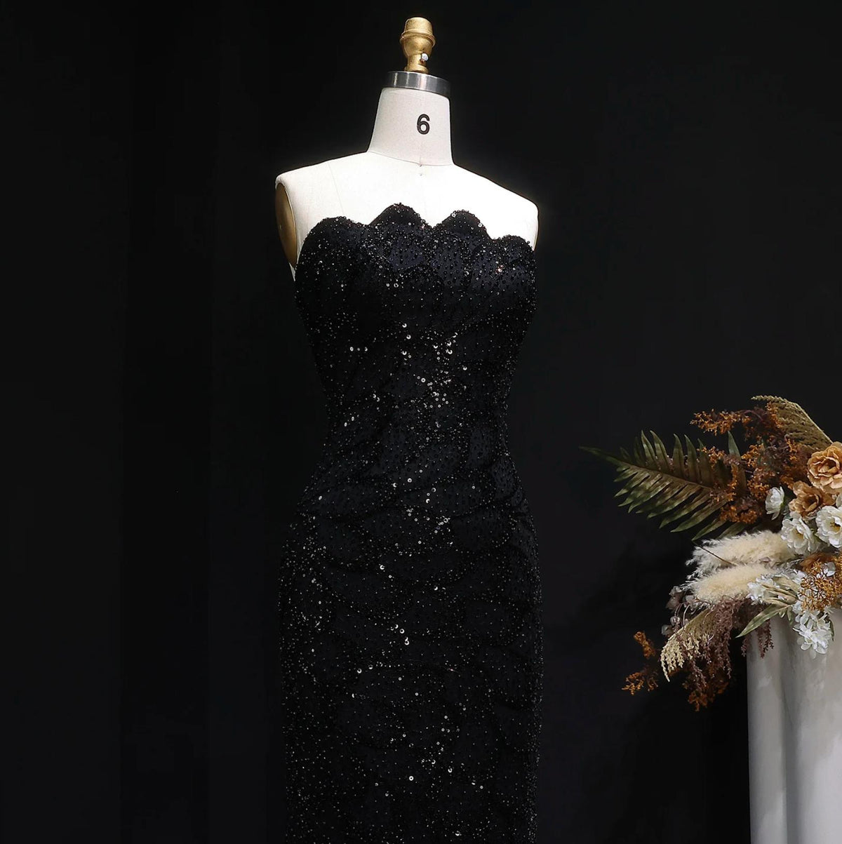 Strapless black mermaid gown with intricate crystal beading and sequin appliqués on a mannequin.
