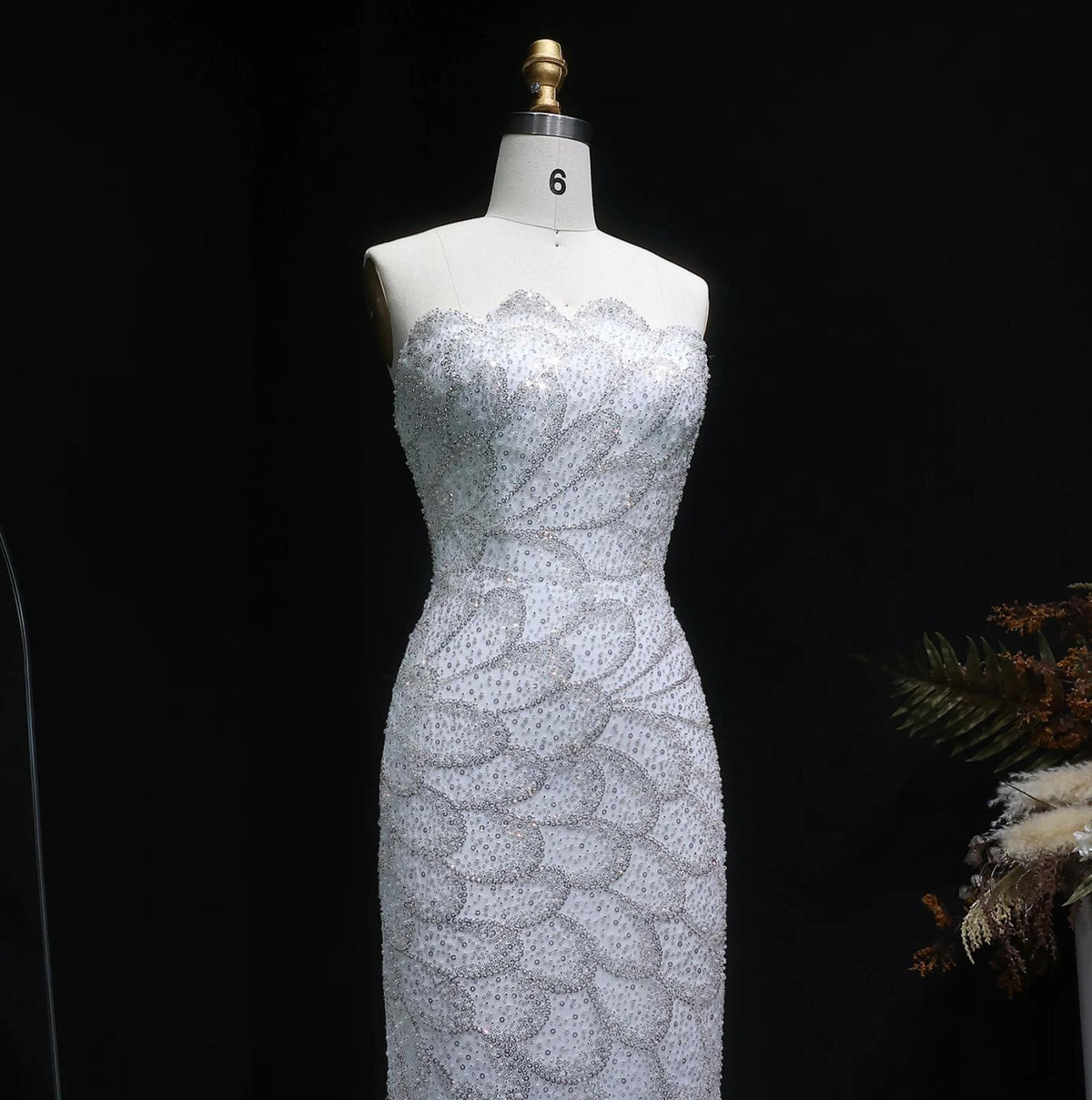 Strapless white mermaid gown featuring intricate crystal beading and scalloped patterns on a mannequin.