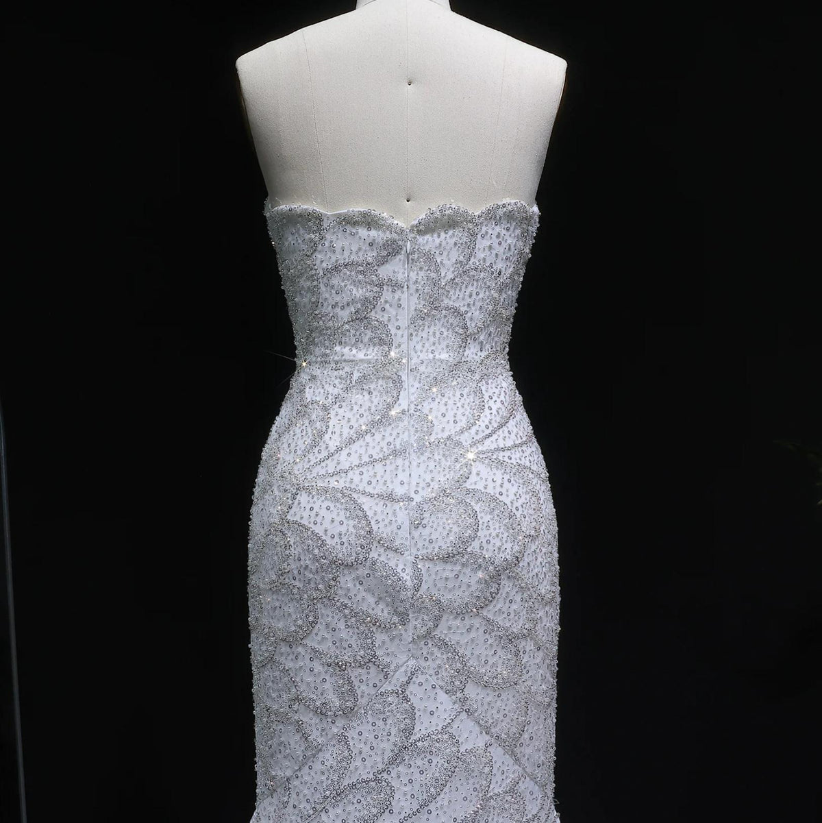 Strapless white mermaid gown featuring intricate silver crystal beading and floral appliqués on a mannequin.