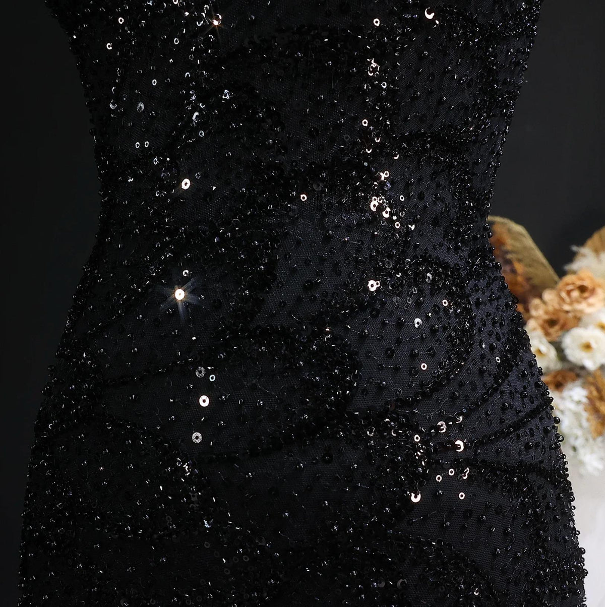 Close-up of a black mermaid gown featuring intricate crystal beading and shimmering sequin appliqués on tulle.