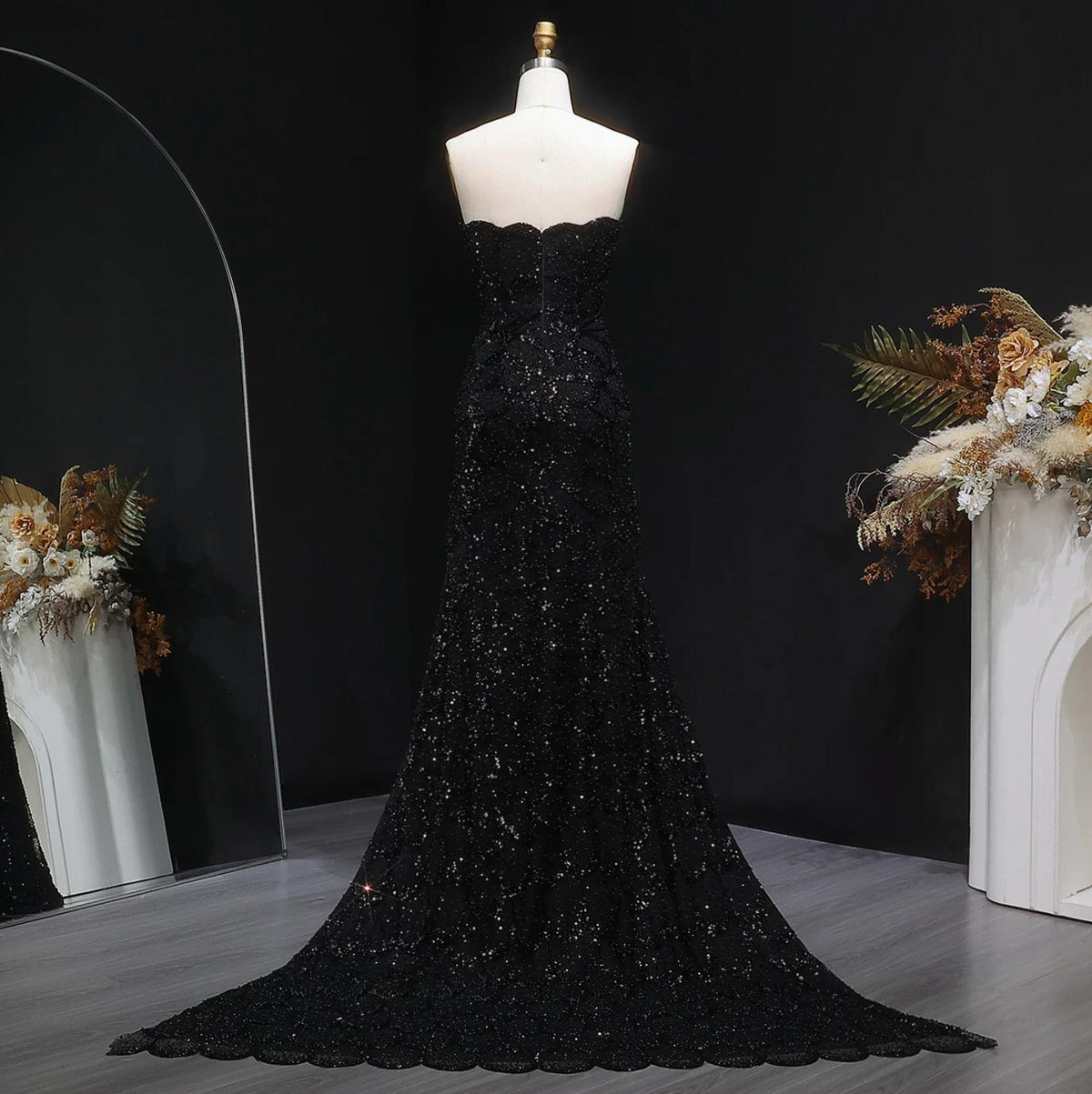 Back view of a strapless black mermaid gown featuring intricate crystal beading, tulle fabric, and a sweeping train.