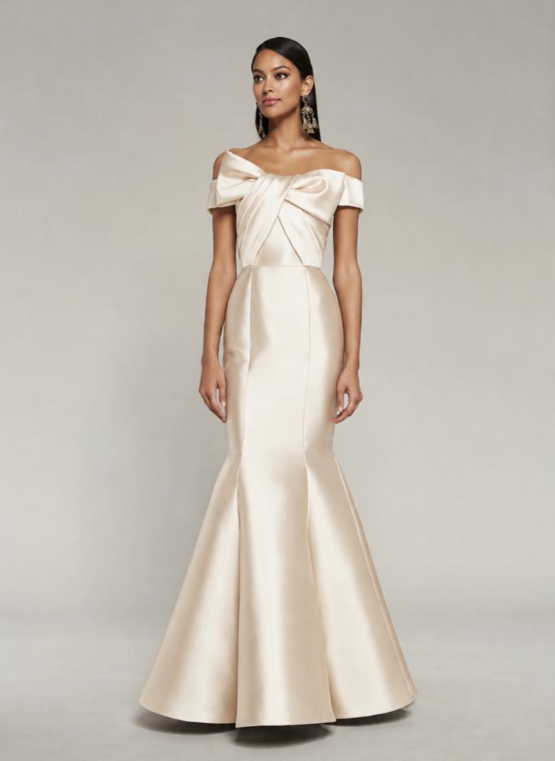 Champagne satin off-the-shoulder mermaid gown featuring a draped bodice with a bow detail and a sculpted floor-length skirt.