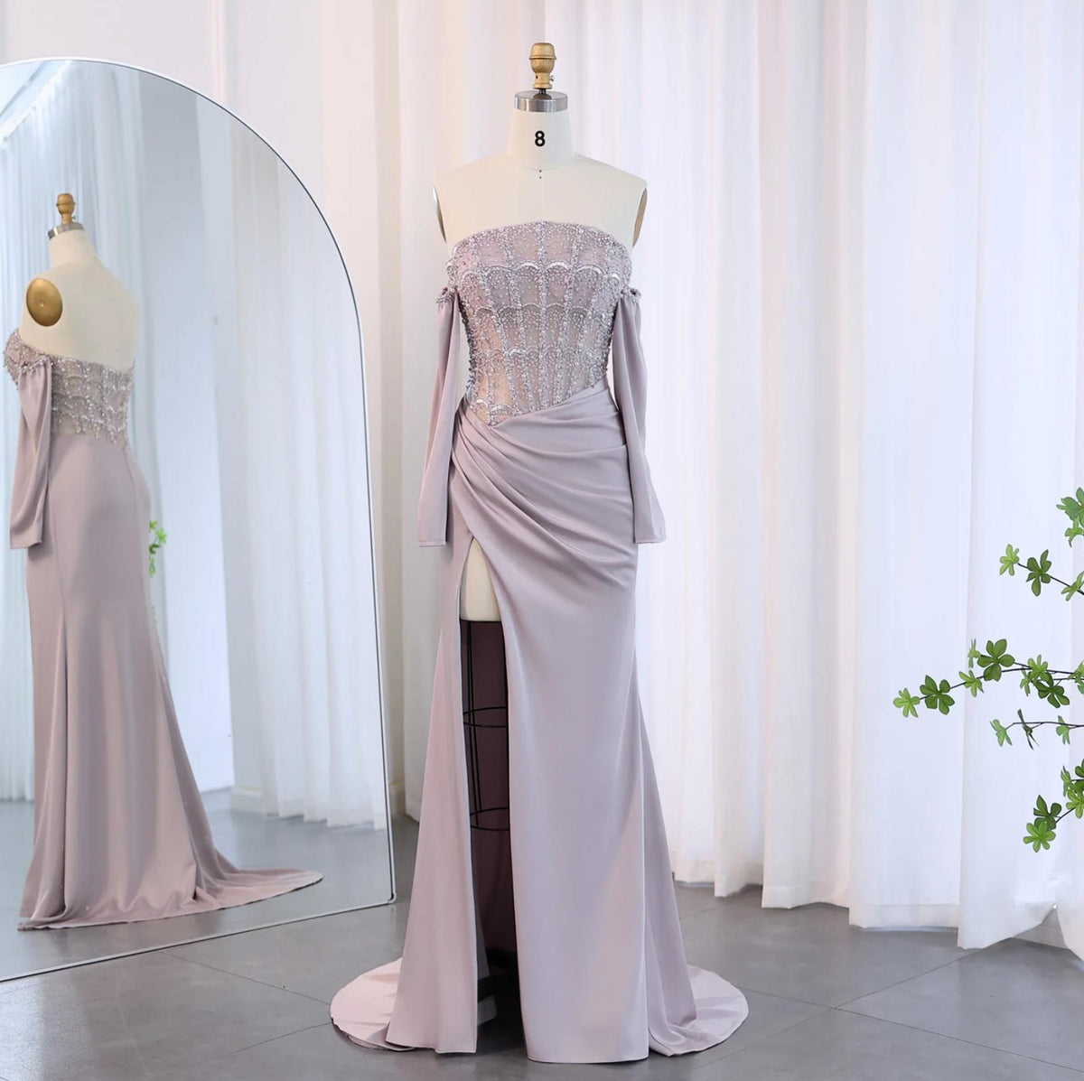 Lavender satin mermaid gown with a beaded bodice, off-the-shoulder sleeves, and a high-slit skirt on a mannequin.