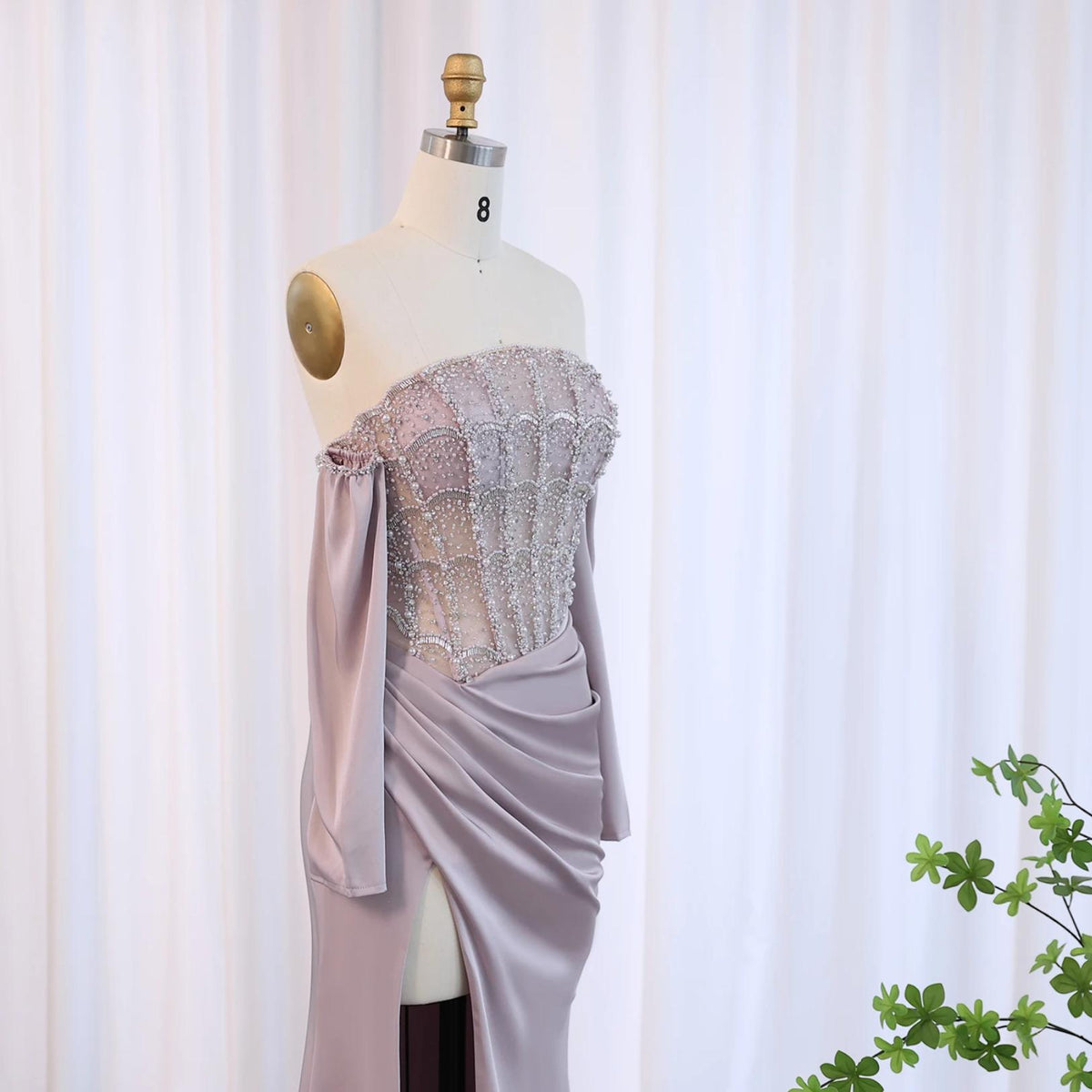 Mauve satin evening gown with a beaded corset bodice, off-the-shoulder sleeves, and a high-slit A-line skirt.