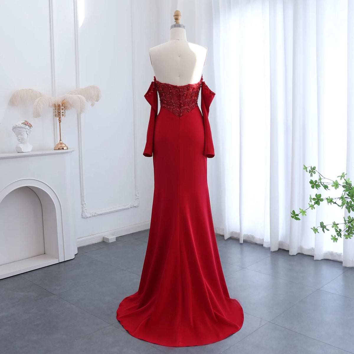 Red satin mermaid evening gown with a beaded bodice, off-the-shoulder sleeves, and a floor-length sweep train.