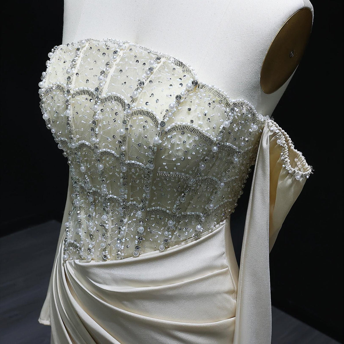 Cream satin evening gown with a beaded, crystal-embellished corset bodice and off-the-shoulder scalloped neckline.