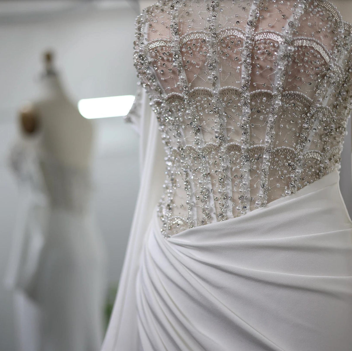 White satin evening gown featuring a beaded corset bodice with intricate crystal and sequin embellishments.
