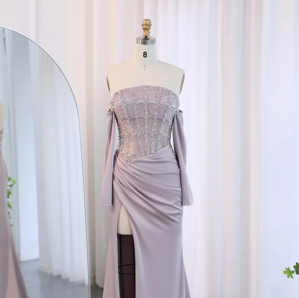Mauve satin evening gown with a beaded corset bodice, off-the-shoulder sleeves, and a high-slit floor-length skirt.