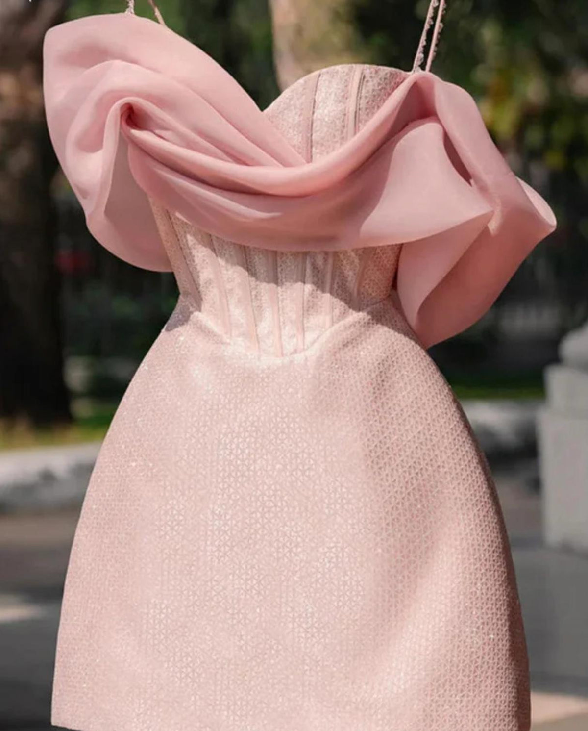 Pink satin mini dress featuring a sweetheart neckline, corset-style bodice, and elegant draped off-shoulder sleeves.