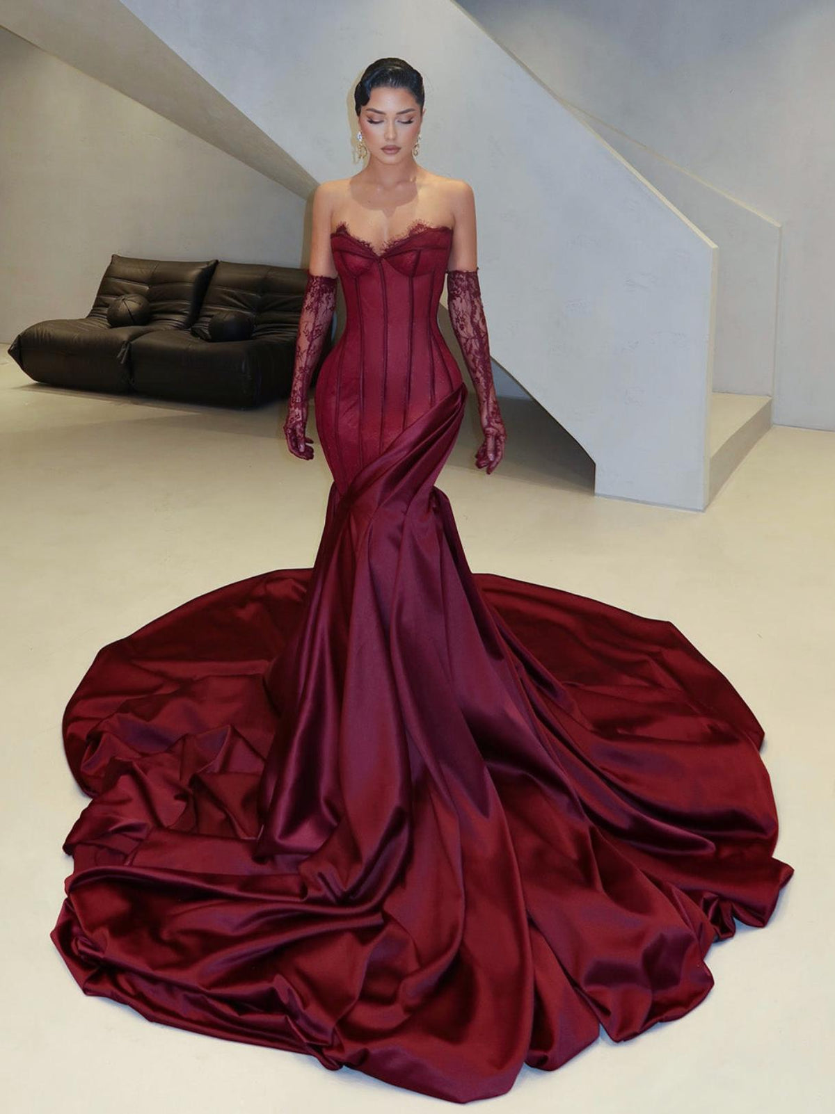 Burgundy satin corset gown with sweetheart neckline, lace detailing, and a dramatic floor-sweeping train with matching gloves.