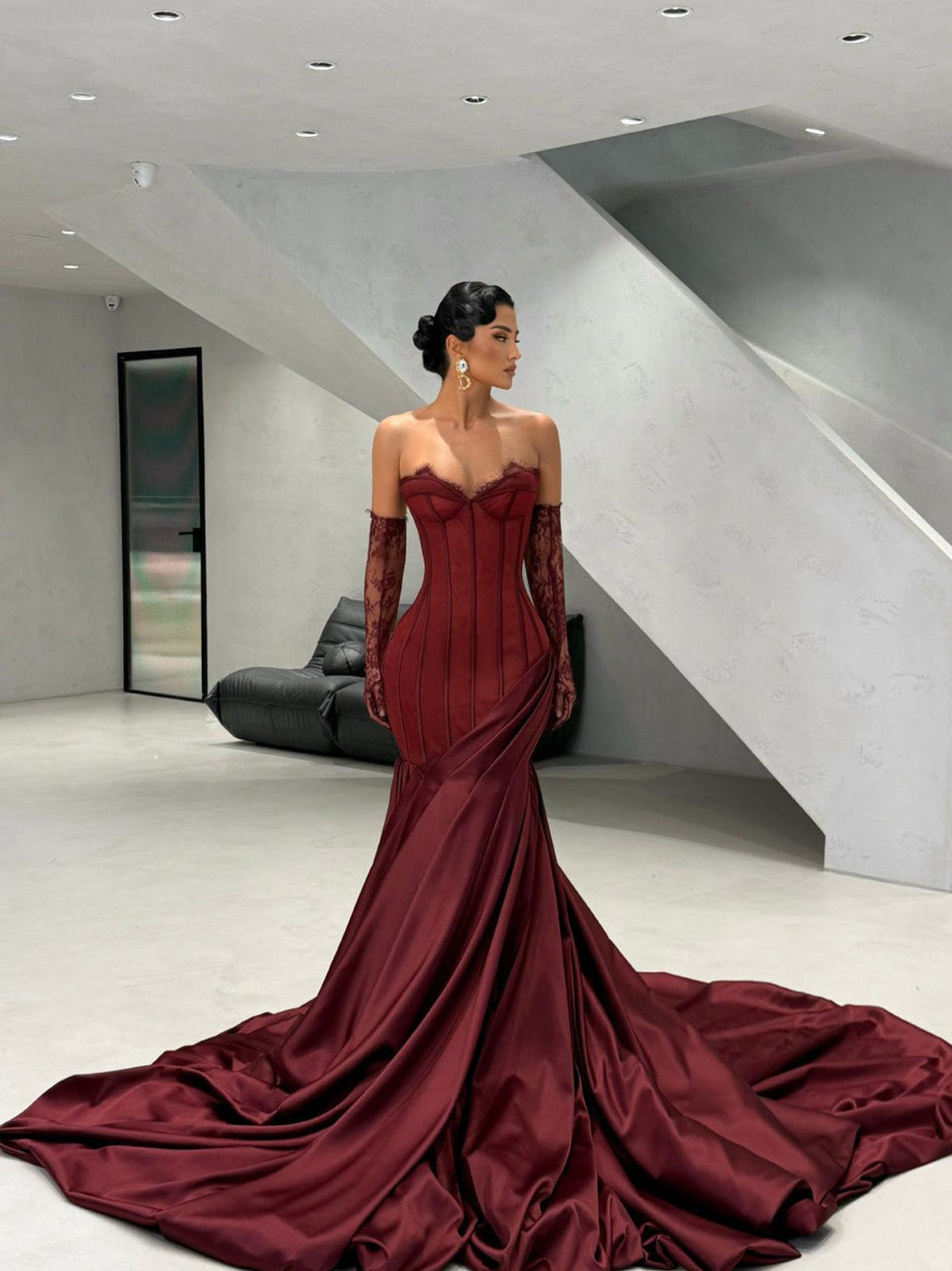 Burgundy satin corset gown with sweetheart neckline, lace detailing, side draping, and matching lace gloves.