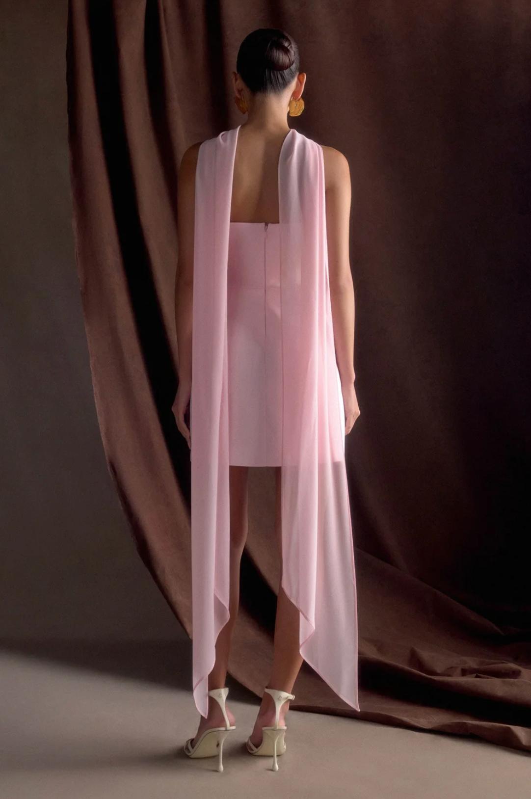 Back view of a light pink satin mini dress with a removable sheer shawl, worn with white strappy heels.