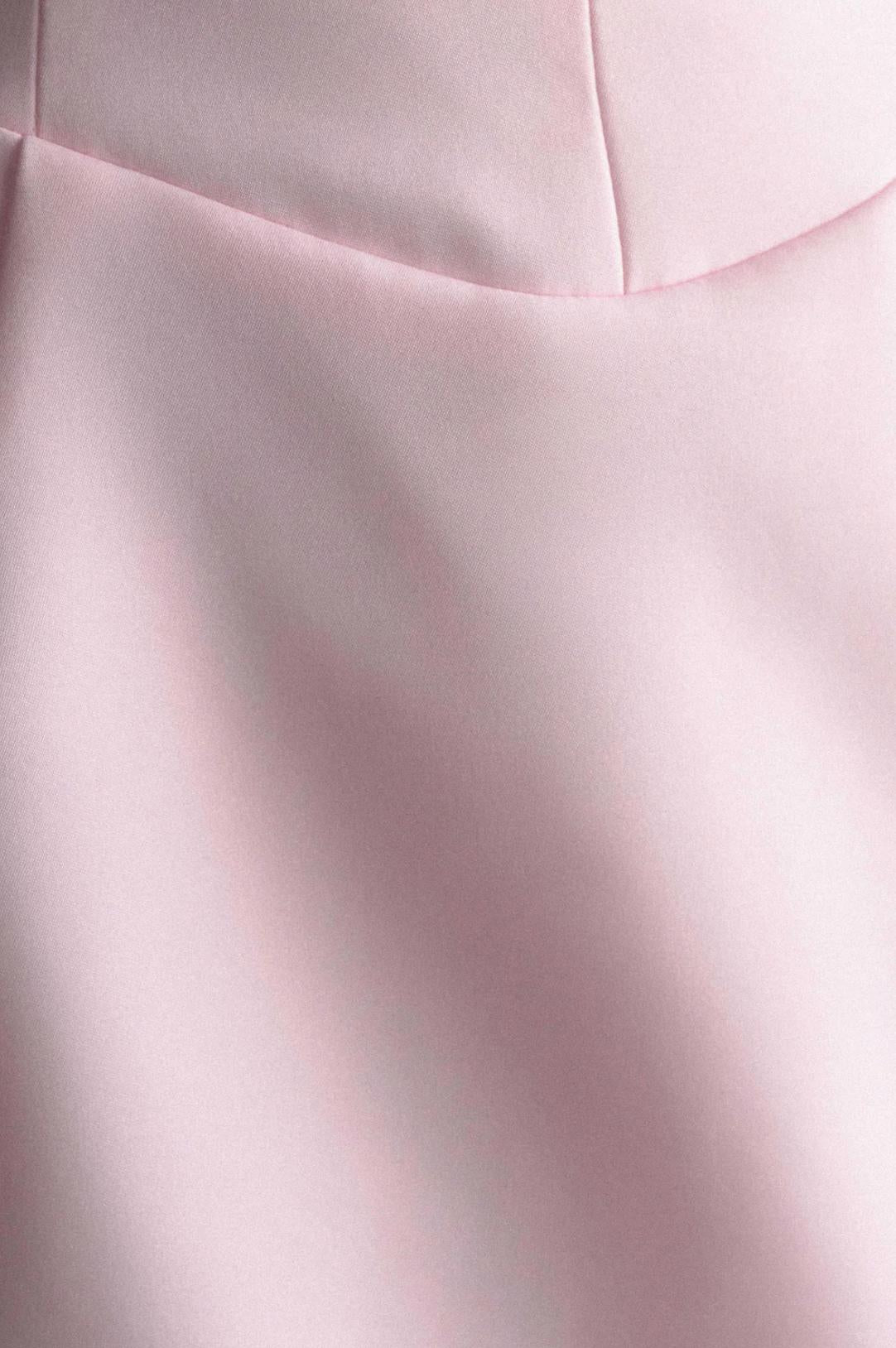 Close-up of a smooth, light pink satin mini dress featuring a structured V-neckline and elegant A-line silhouette.