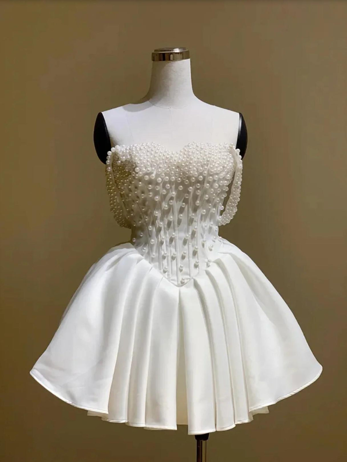 White silk bridal mini dress with an off-the-shoulder neckline, corset bodice, and delicate pearl embellishments.