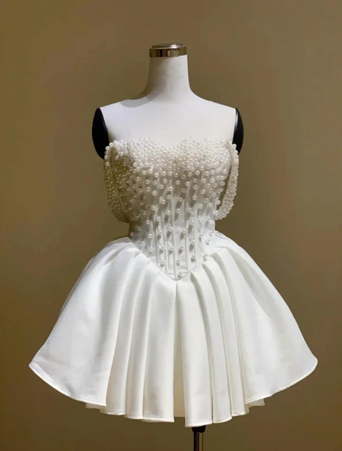 White silk mini bridal dress with an off-the-shoulder neckline, pearl embellishments, and a structured A-line skirt.