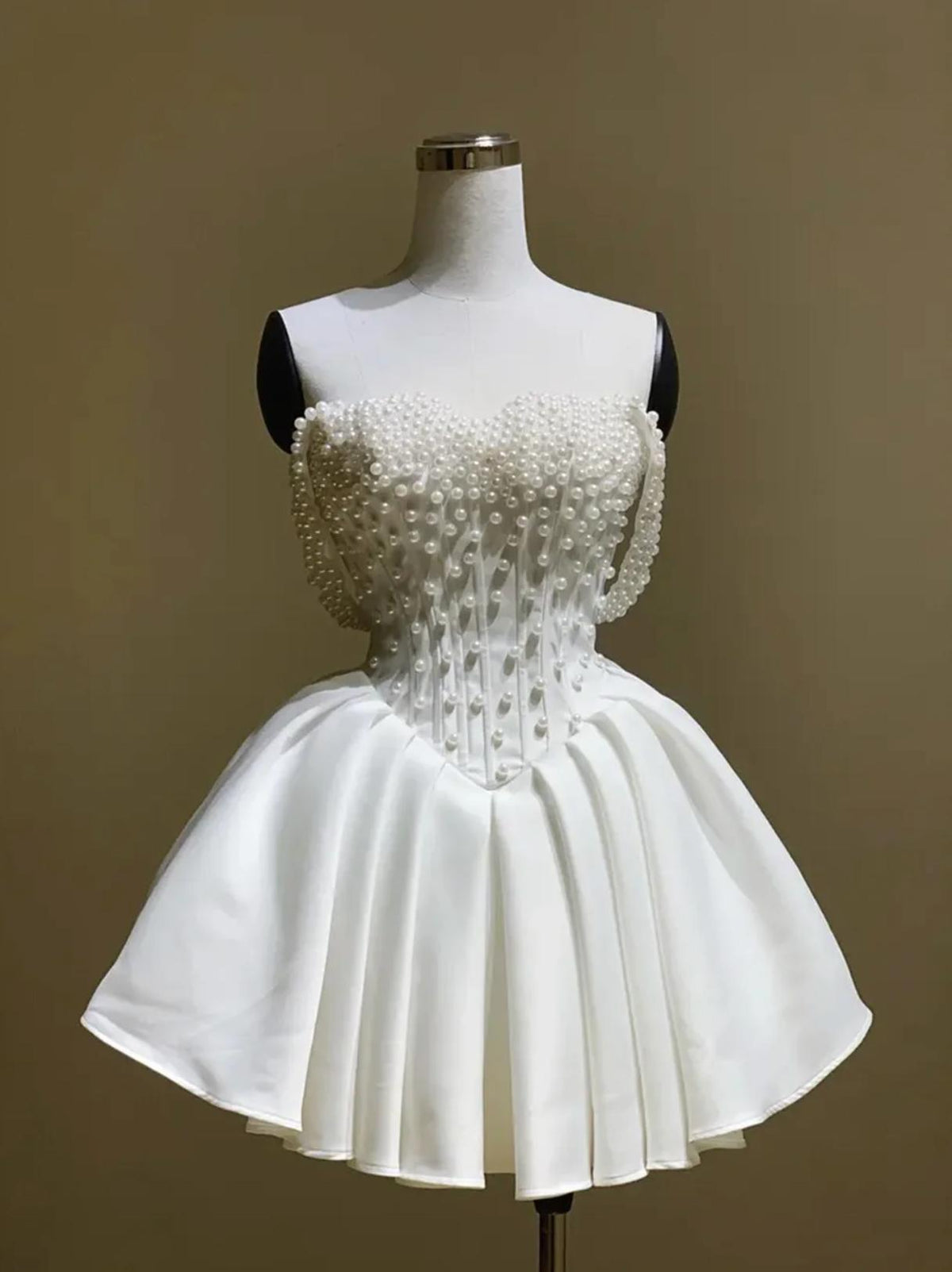 White silk bridal mini dress with an off-the-shoulder neckline and intricate pearl embellishments on a mannequin.