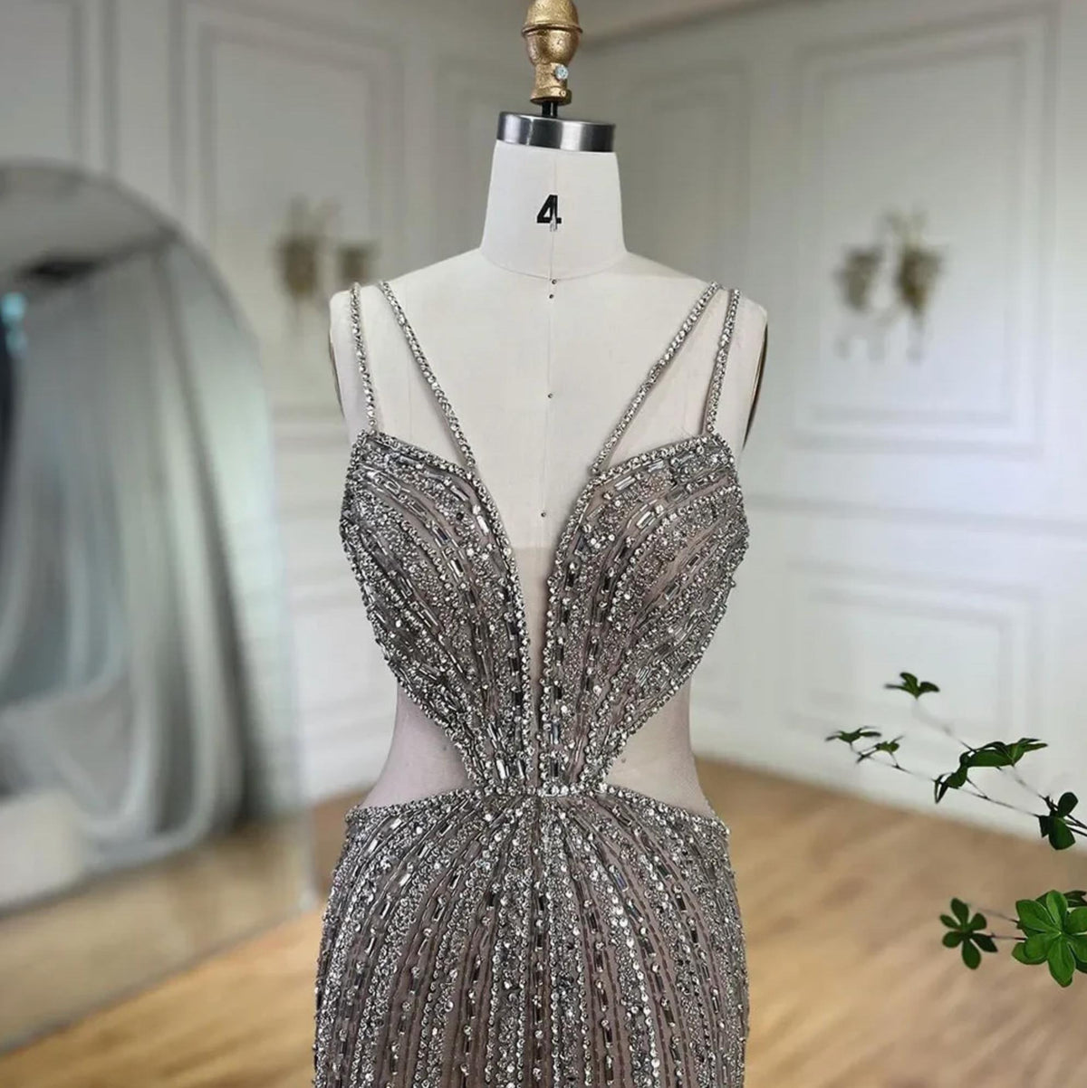Nude tulle mermaid gown with a V-neck, spaghetti straps, and intricate silver crystal and sequin beadwork.