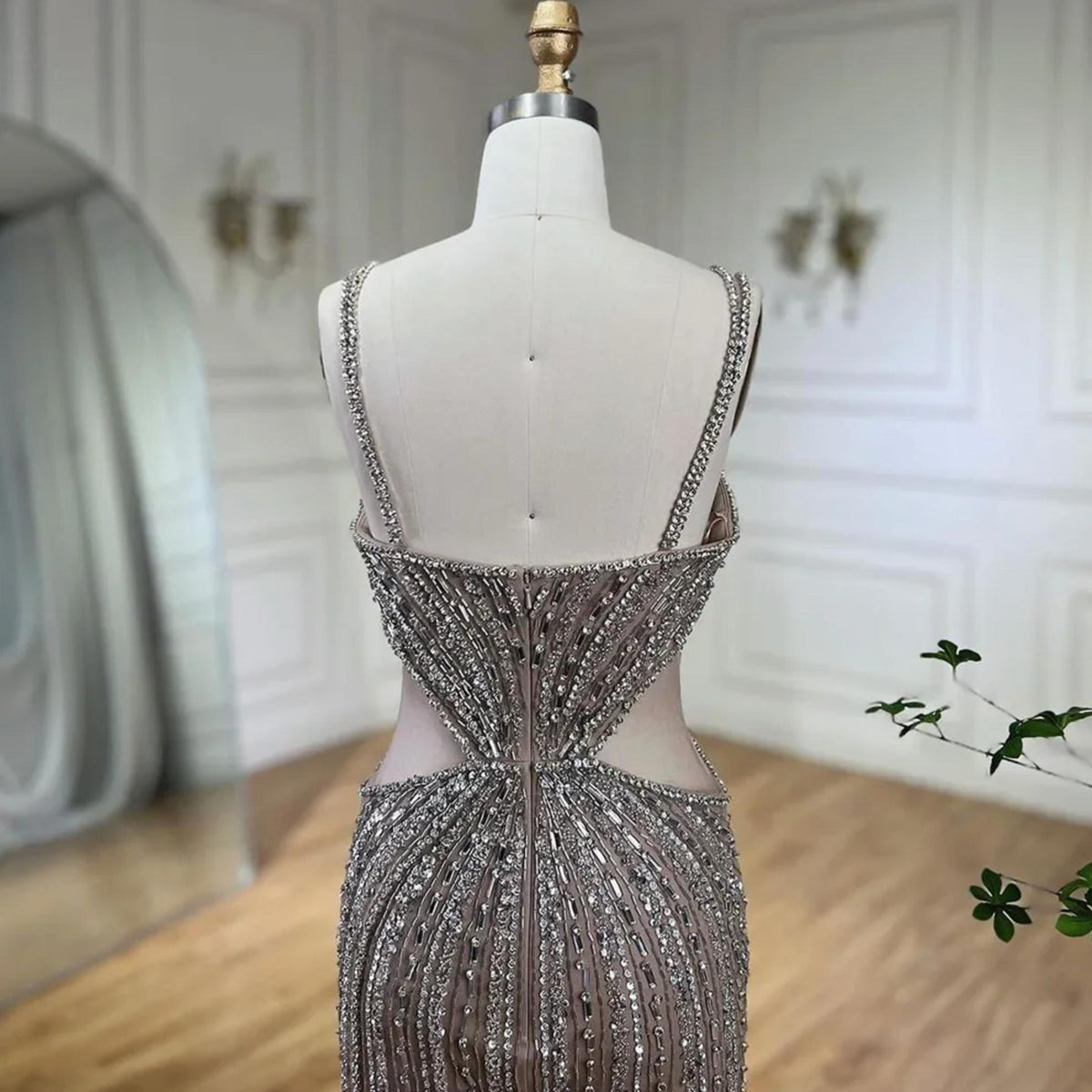 Nude mermaid evening gown with intricate crystal and sequin beading, spaghetti straps, and sheer tulle side cutouts.