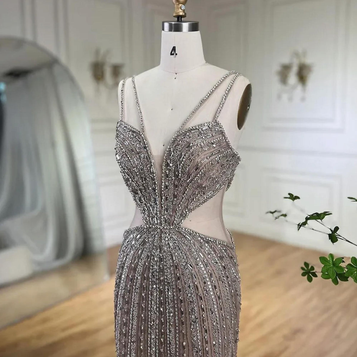 Nude mermaid evening gown with a V-neckline, spaghetti straps, and intricate silver crystal and sequin beadwork on tulle.