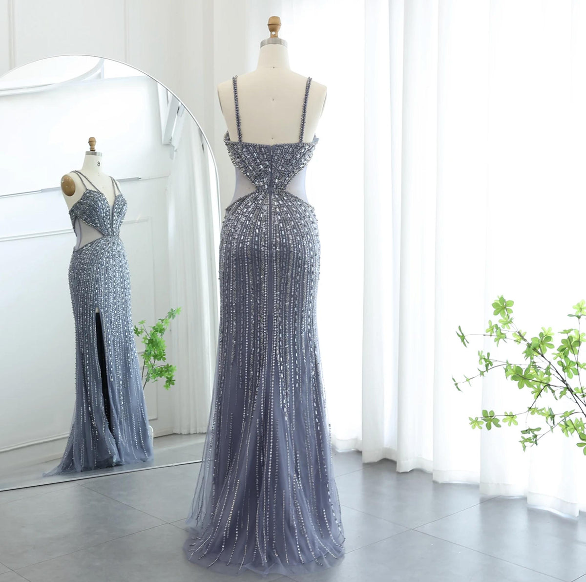 Nude mermaid evening gown with intricate beading, sequins, spaghetti straps, and a high slit on a mannequin.