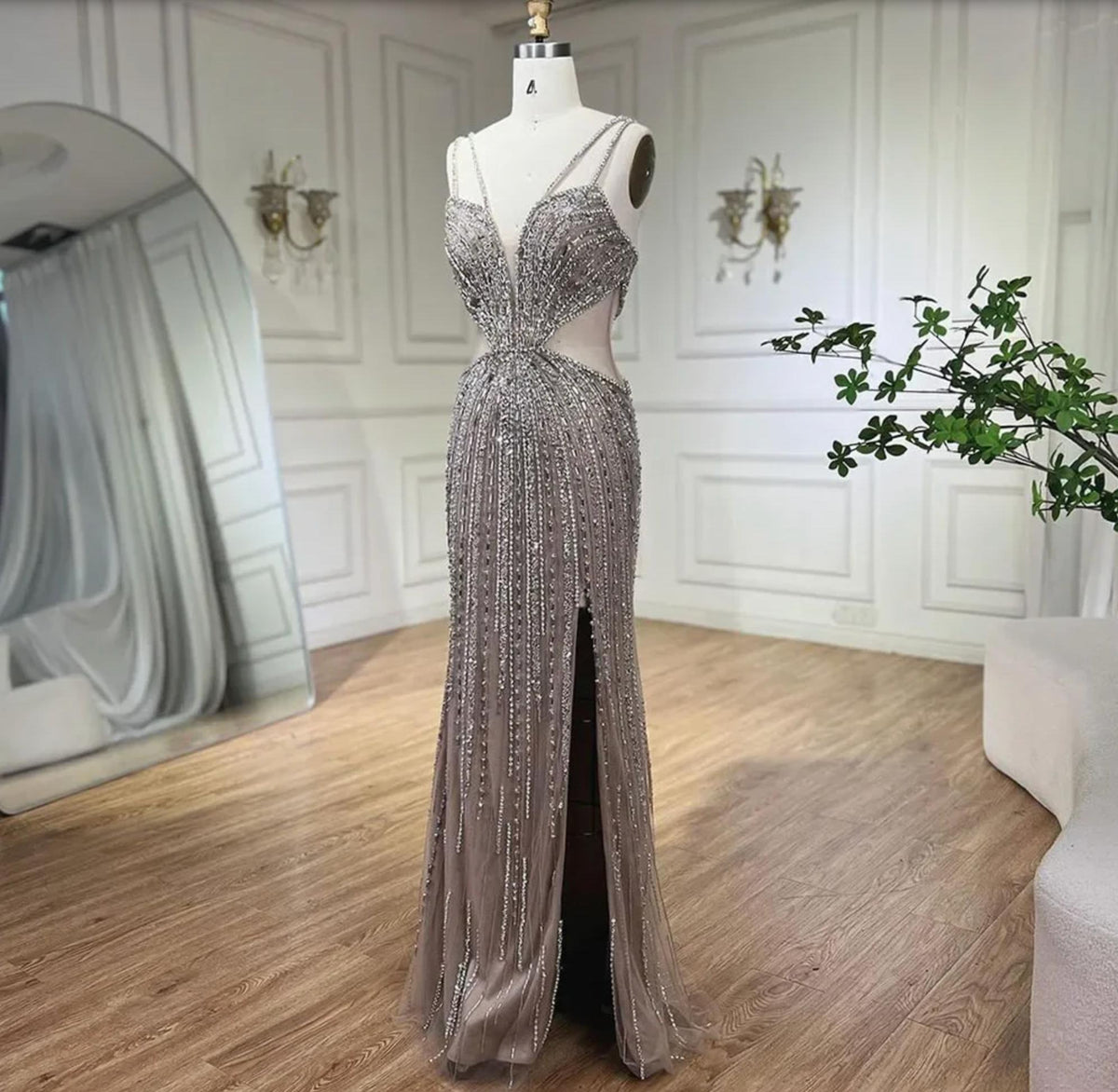 Nude mermaid evening gown with V-neck, spaghetti straps, high slit, and intricate silver crystal and sequin beadwork.