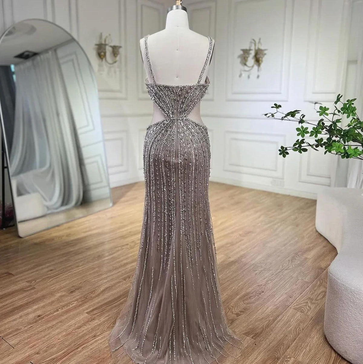 Nude mermaid evening gown with intricate silver beading, sequins, spaghetti straps, and a sheer tulle floor-length train.