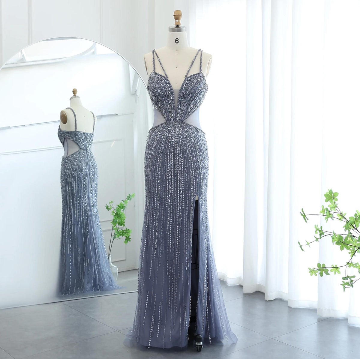 Grey tulle mermaid evening gown with V-neck, spaghetti straps, intricate crystal beading, and a high leg slit on a mannequin.