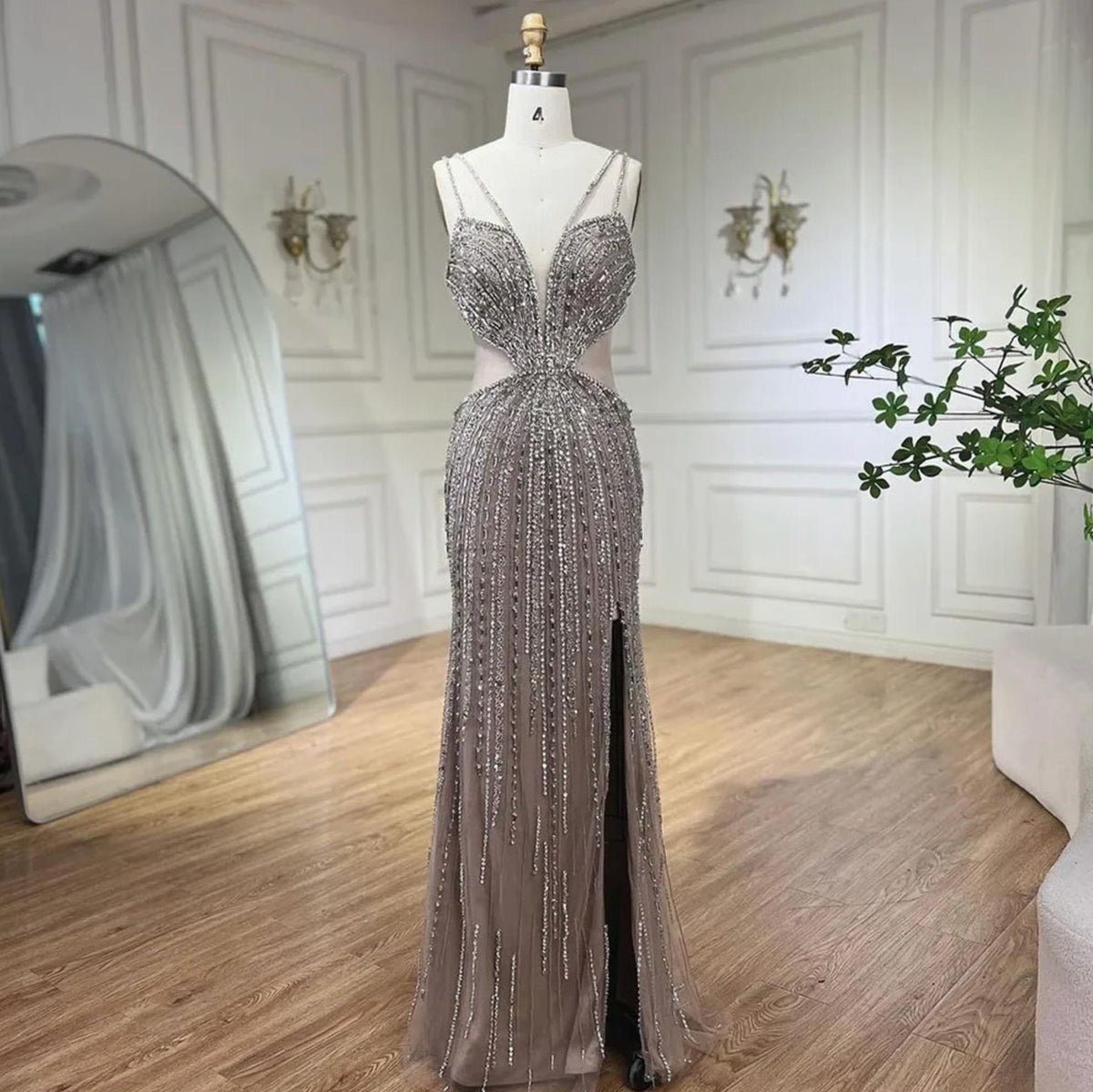 Nude mermaid evening gown with V-neck, spaghetti straps, high slit, and intricate crystal and sequin beading on tulle.