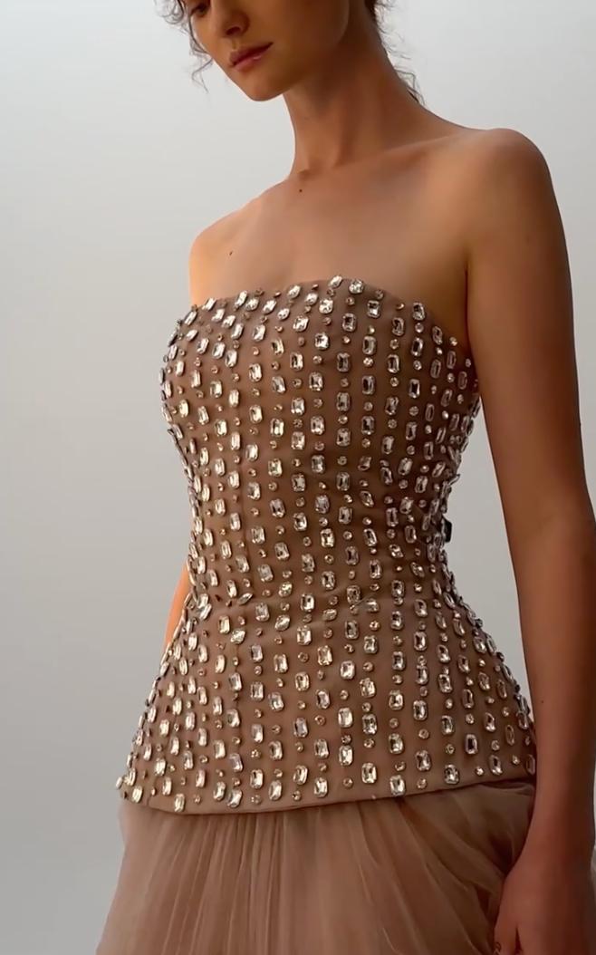 Strapless nude illusion gown featuring a beaded bodice with sparkling diamond embellishments and a layered tulle skirt.
