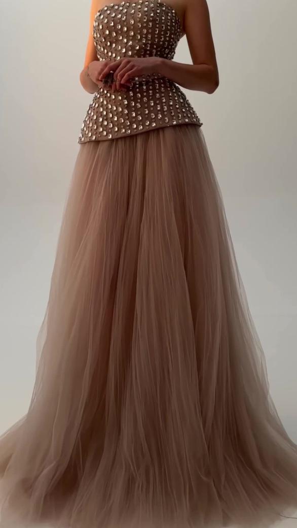 Strapless nude gown with diamond-embellished bodice and voluminous floor-length tulle skirt.