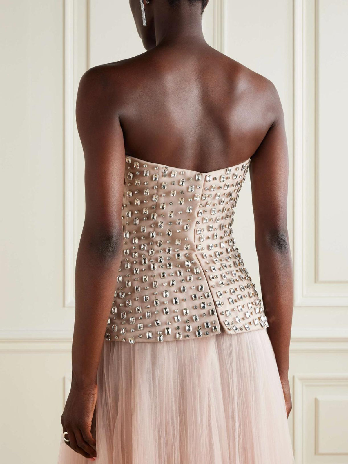 Strapless nude gown with a crystal-embellished bodice and a flowing tulle skirt, viewed from the back.