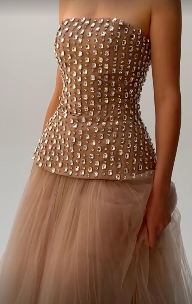 Strapless nude gown with a beaded bodice featuring sparkling diamond embellishments and a layered tulle A-line skirt.