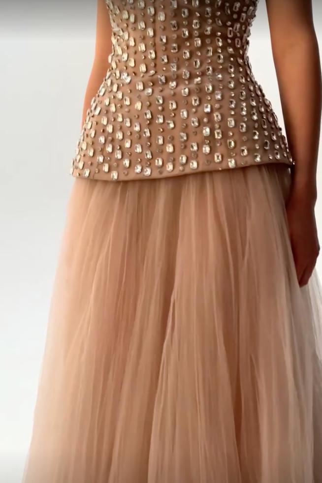 Nude strapless gown with a crystal-beaded bodice and a voluminous floor-length tulle skirt for formal events.