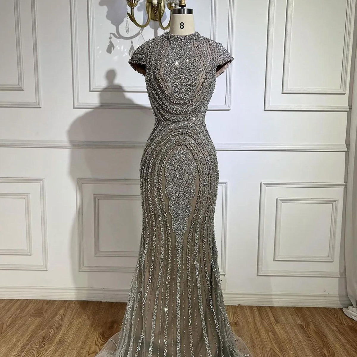 Gray nude mermaid evening gown with intricate silver beading on tulle, short sleeves, and a round neckline on a mannequin.