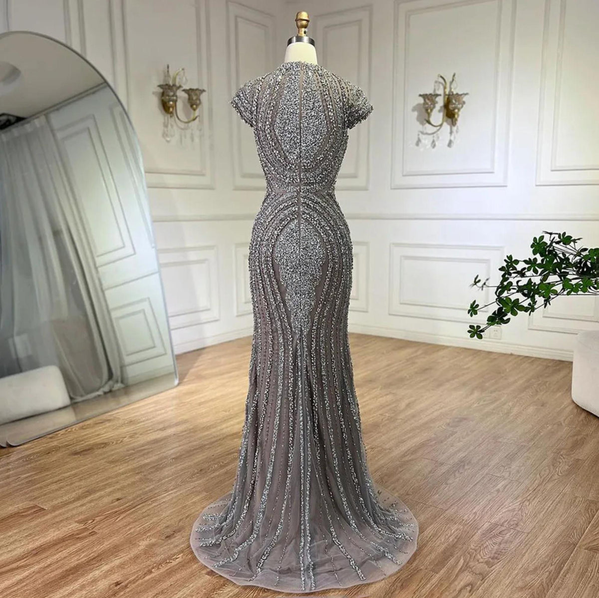 Gray nude mermaid evening gown with intricate silver beading on tulle, short sleeves, and a court train on a mannequin.