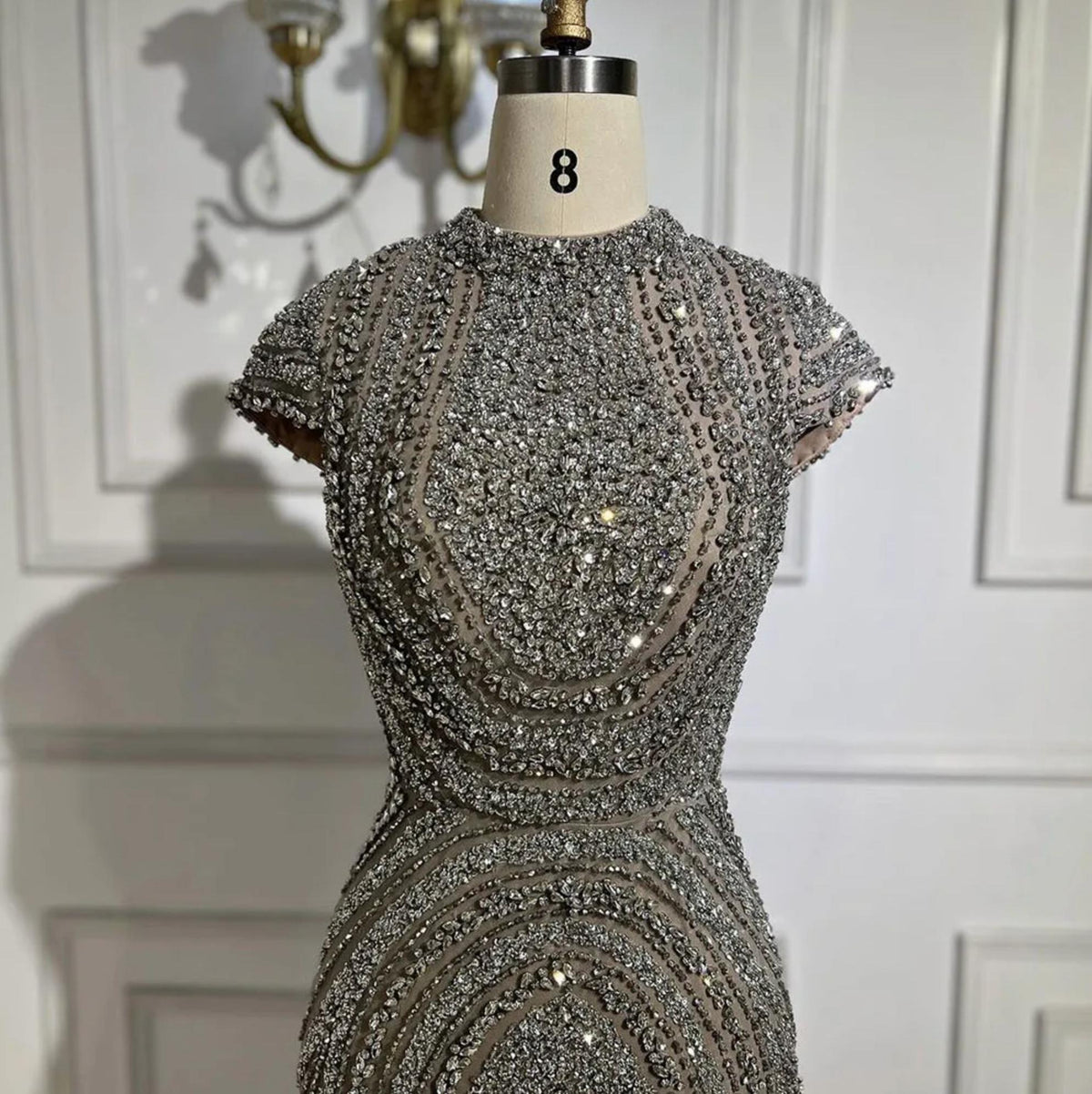 Gray nude mermaid gown with intricate silver beading on tulle, short sleeves, and a round neckline on a size 8 mannequin.