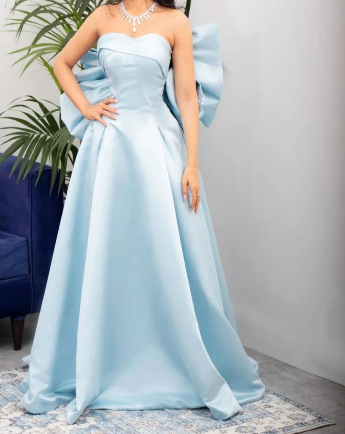 Light blue strapless satin A-line gown with a dramatic back bow and elegant floor-length silhouette.