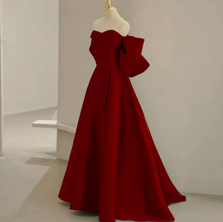 Regina Gown in deep red satin with a strapless off-the-shoulder neckline and dramatic bow detail on an A-line skirt.