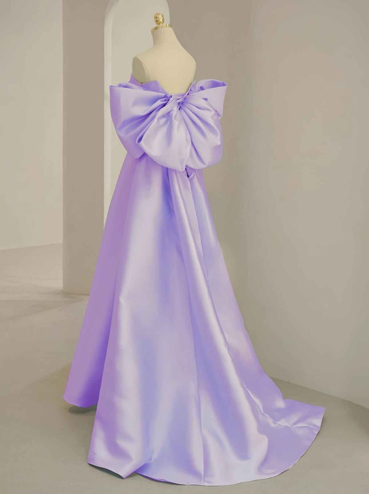 Lavender satin A-line Regina gown featuring a strapless neckline and a large statement bow on the back.