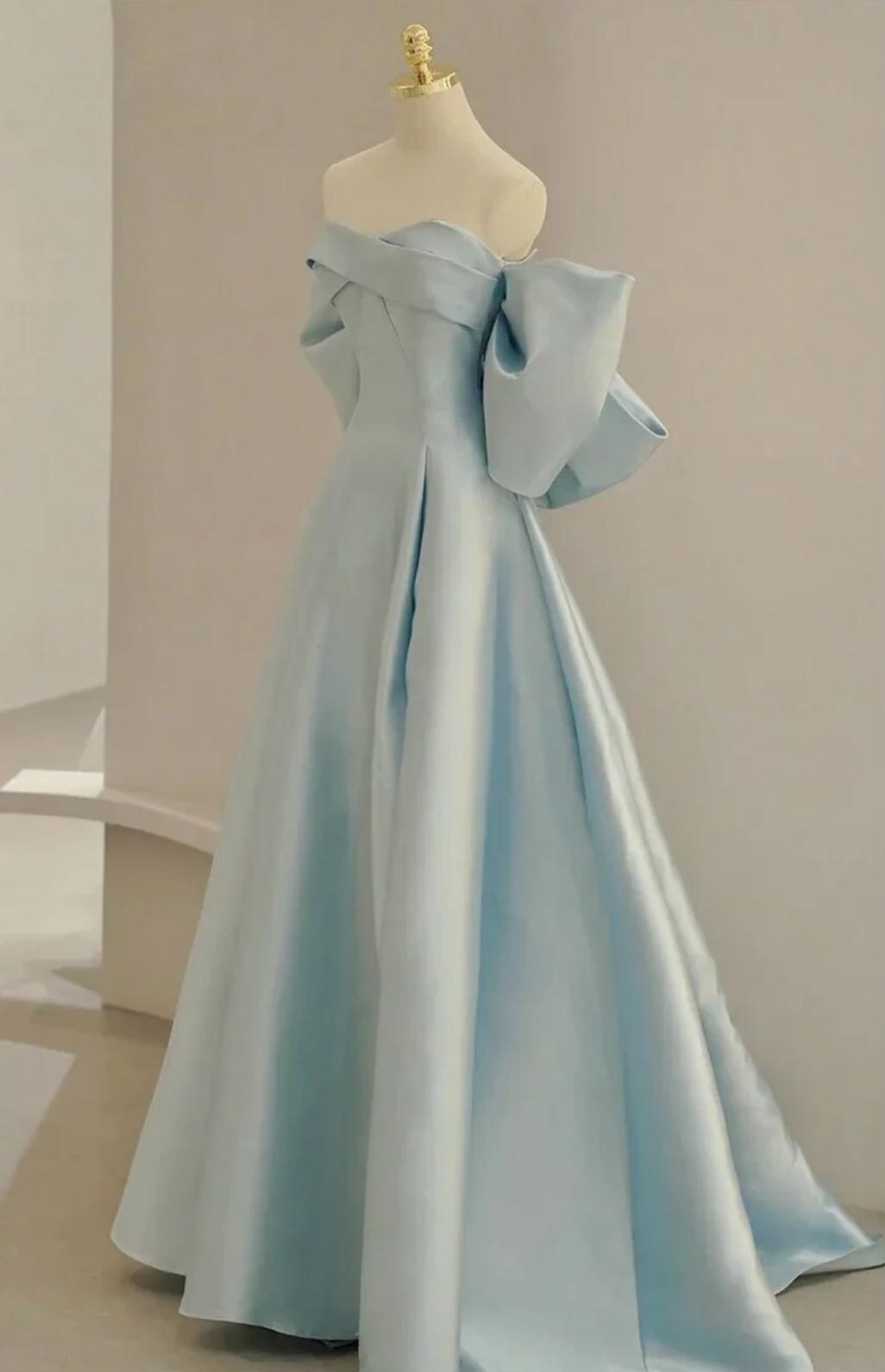 Light blue satin A-line evening gown with an off-the-shoulder neckline and dramatic bow detail on a mannequin.