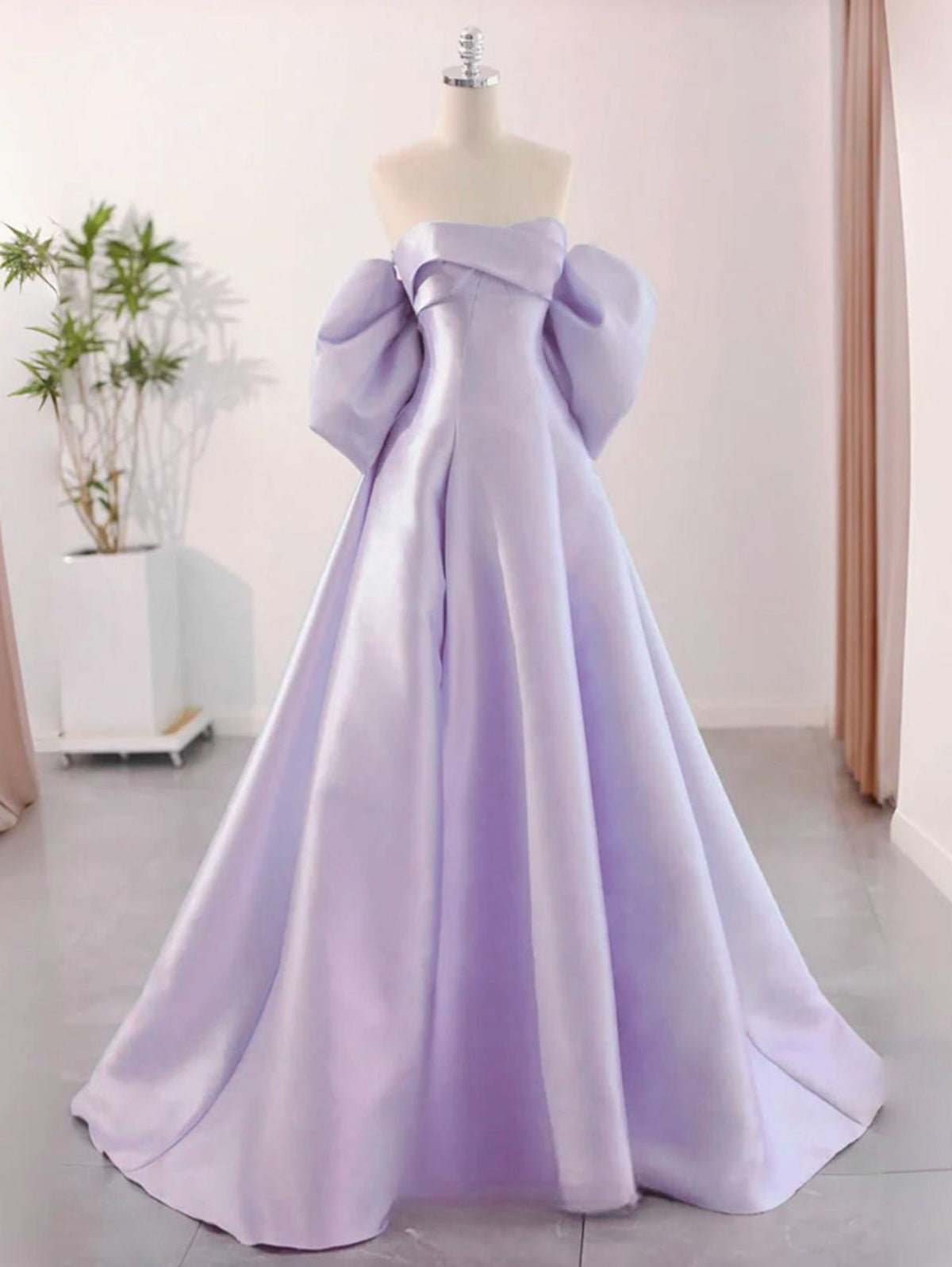 Lavender satin A-line evening gown with a strapless neckline and dramatic puff sleeves on a mannequin.