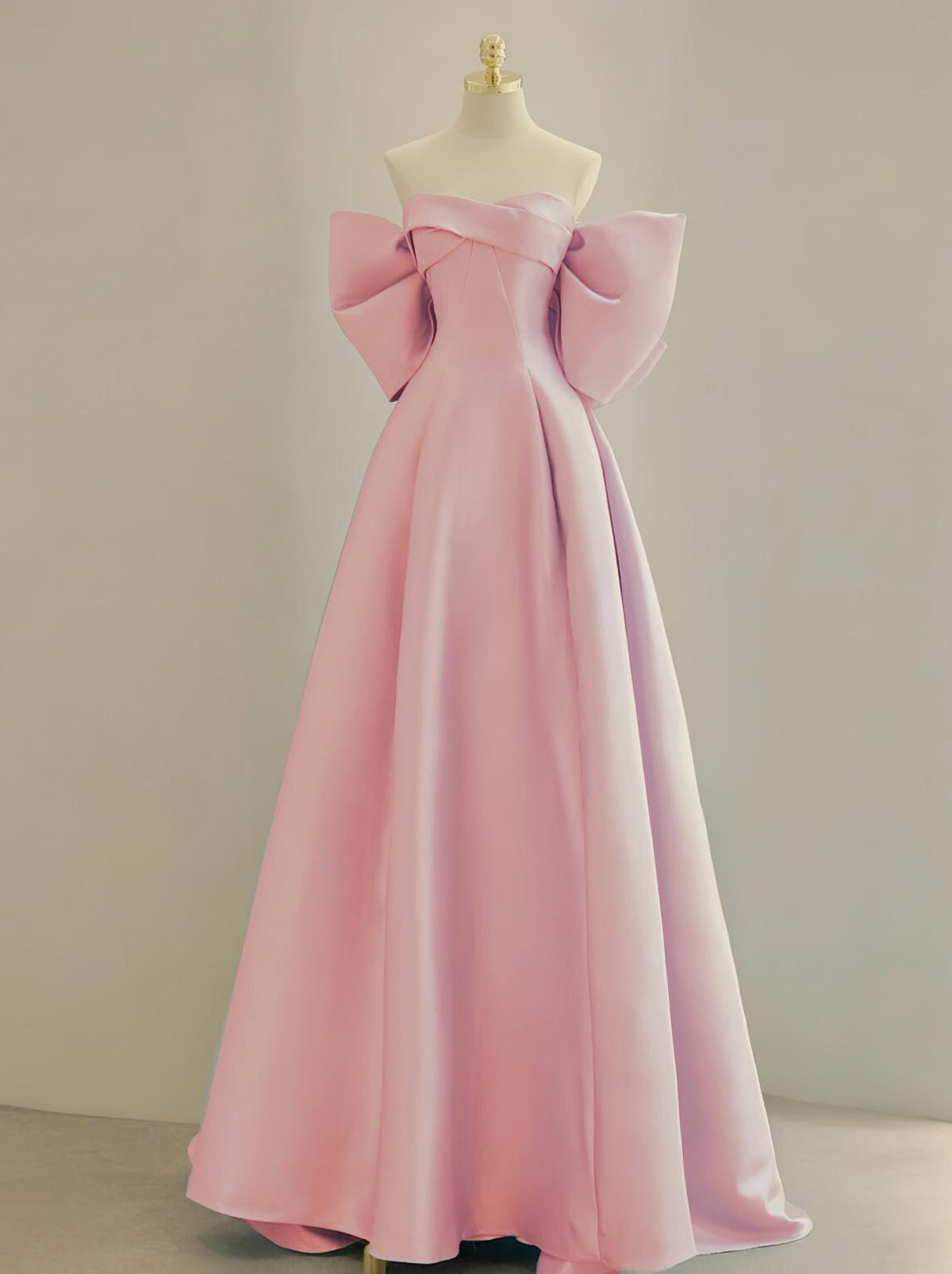 Pink satin A-line Regina gown with an off-the-shoulder boat neckline and dramatic oversized bow sleeves.