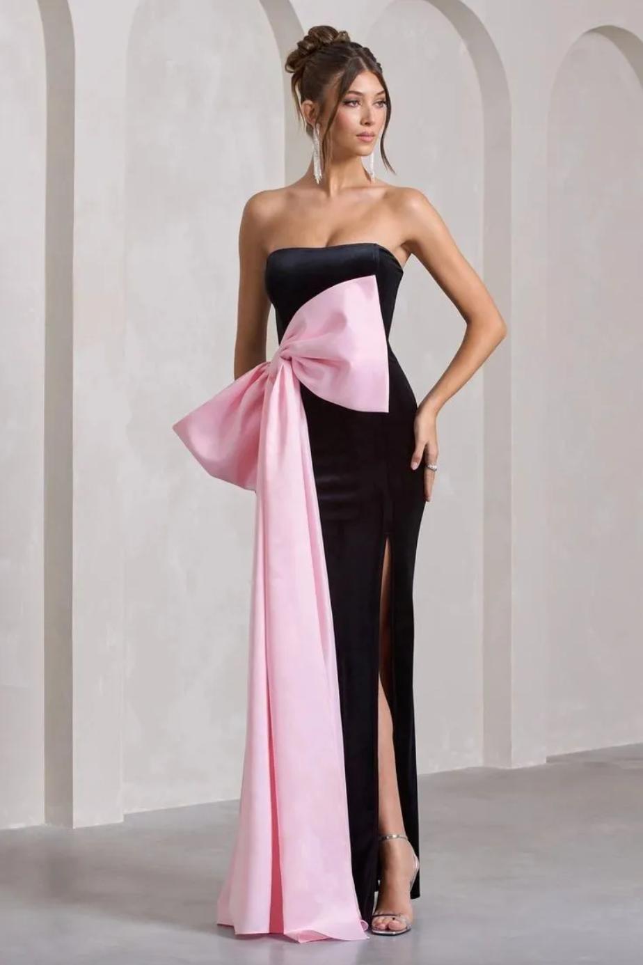 Strapless black satin gown featuring a large pink bow, side slit, and sleek floor-length silhouette for formal events.