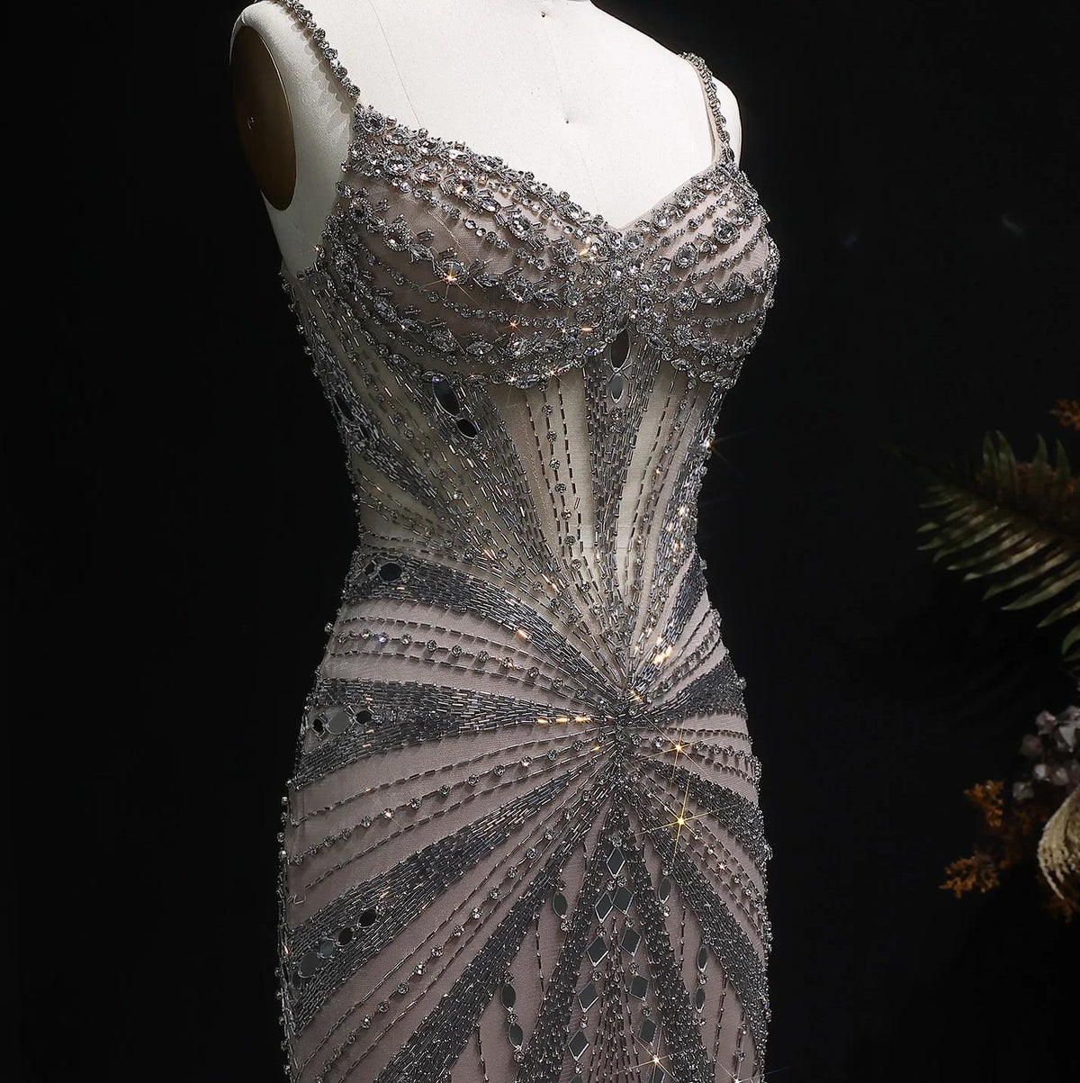 Champagne satin evening gown featuring intricate crystal beading, spaghetti straps, and a sheer, form-fitting silhouette.