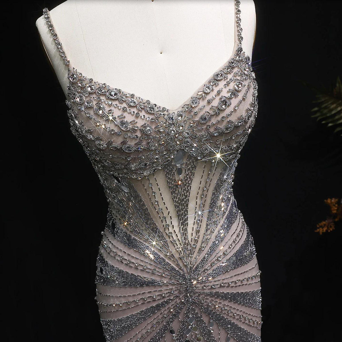 Champagne satin evening gown featuring intricate crystal beading, spaghetti straps, and a sheer, form-fitting design.