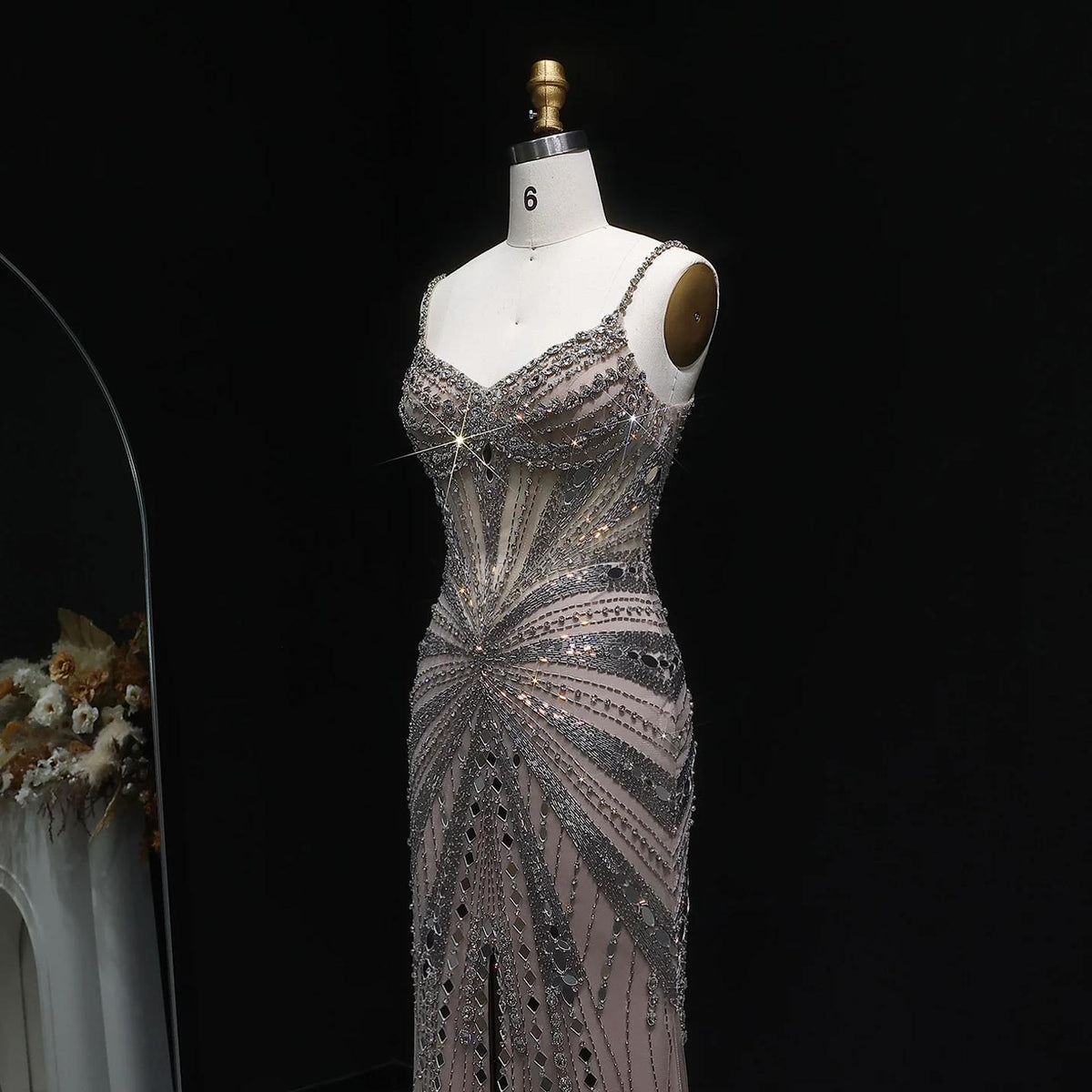Champagne satin evening gown with intricate crystal beading, spaghetti straps, and a sheer, form-fitting silhouette.