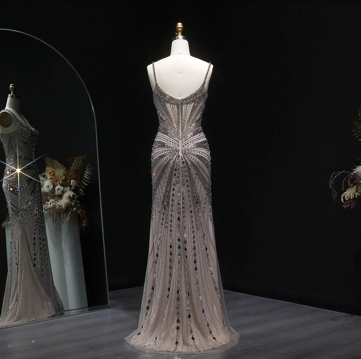 Champagne satin backless gown with intricate crystal beading, spaghetti straps, and a floor-length silhouette.