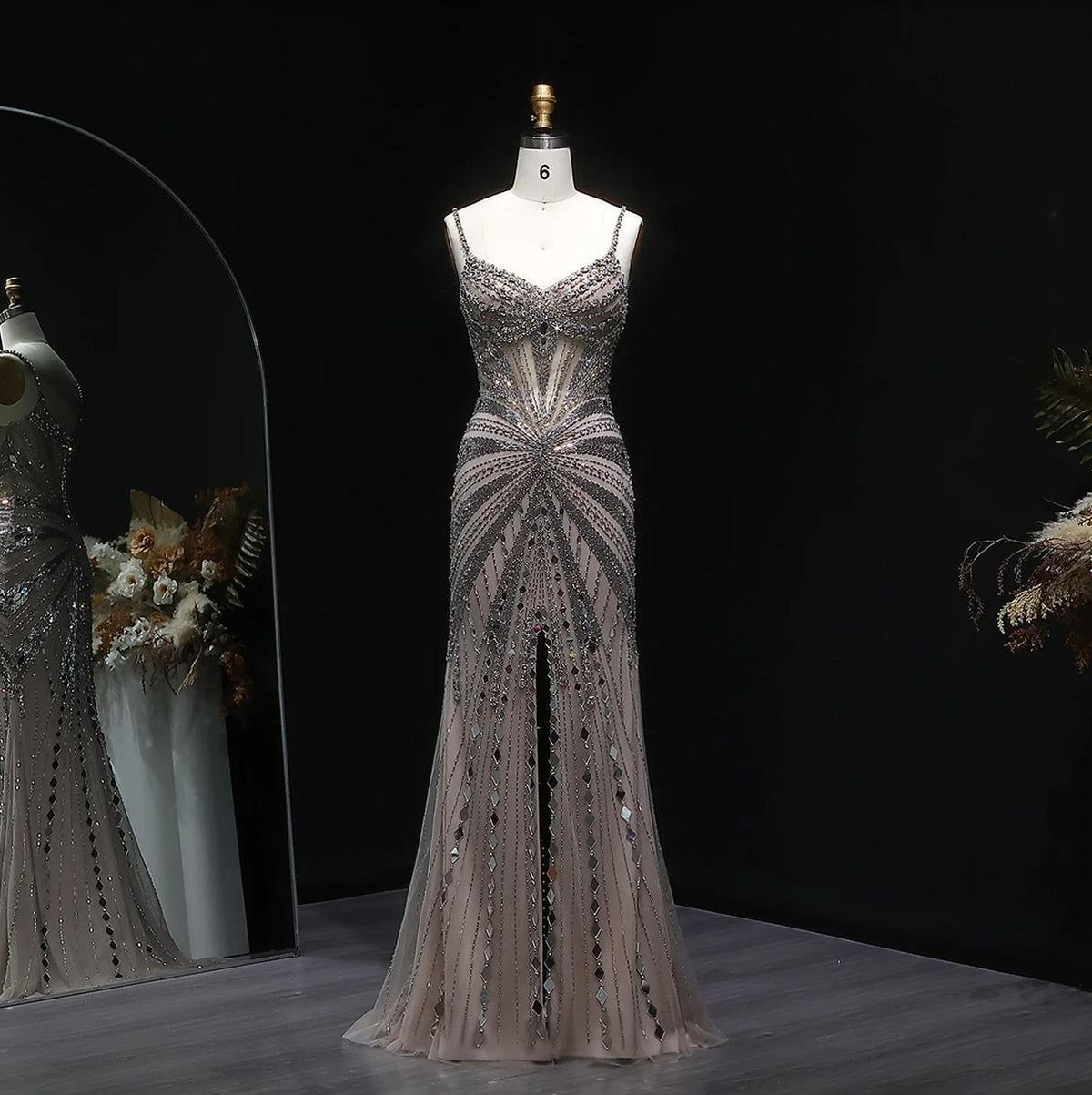 Champagne satin evening gown featuring intricate crystal beading, spaghetti straps, and a sheer floor-length silhouette.