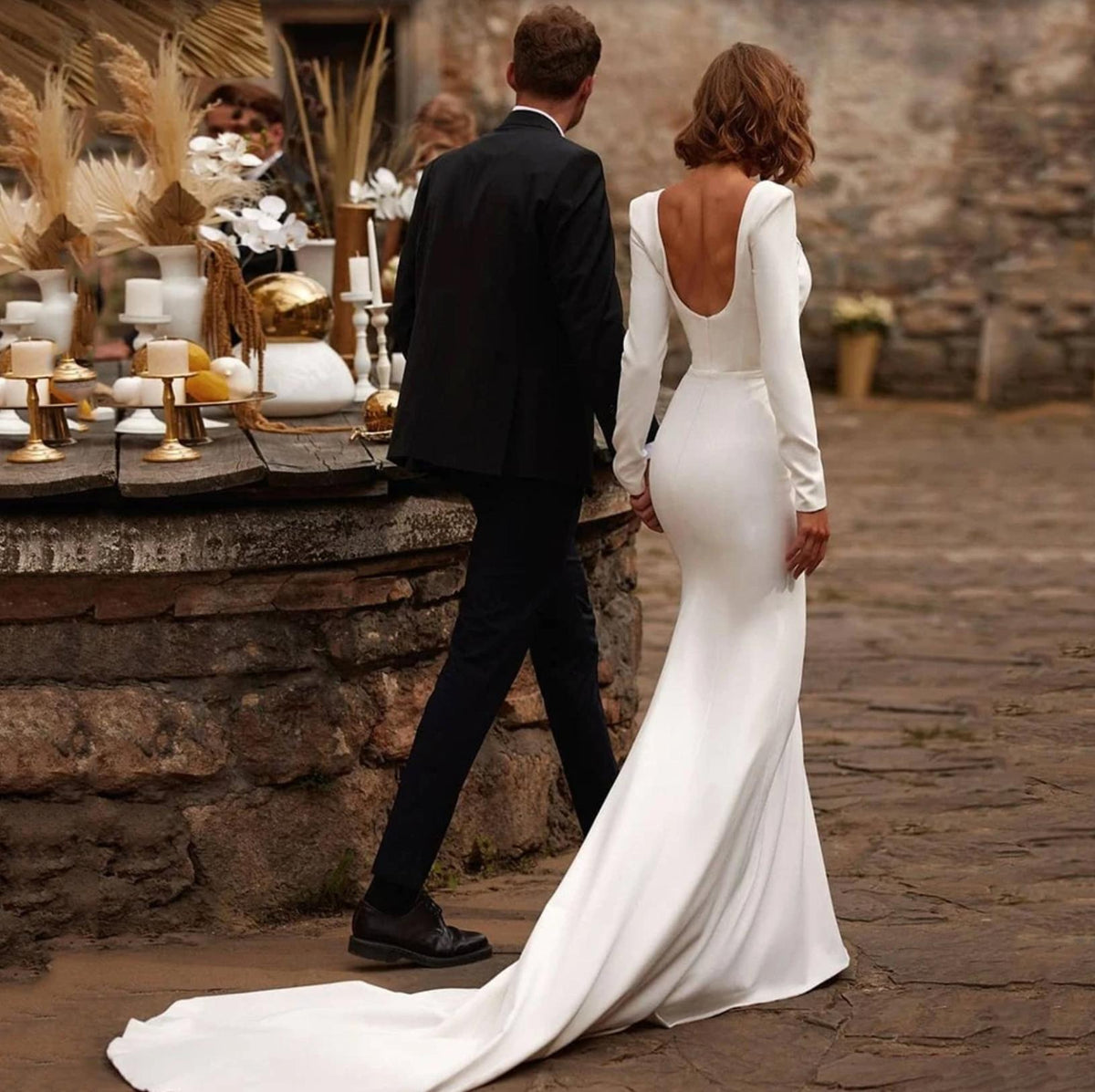 White satin mermaid gown with long sleeves, a square neckline, and a low back with a sweeping court train.