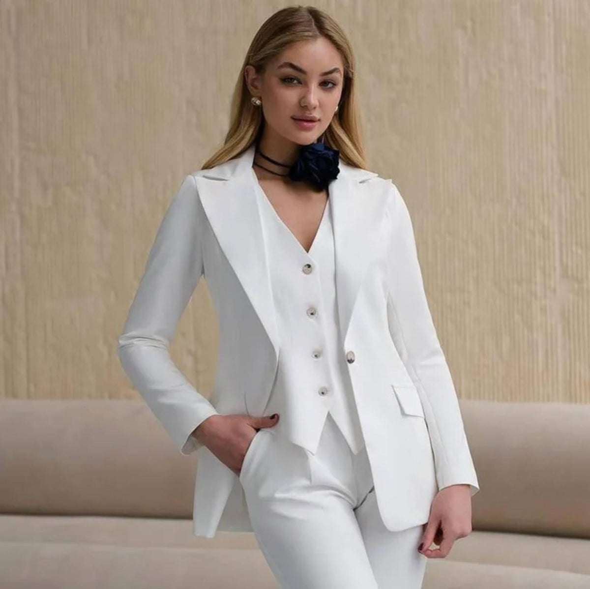Woman wearing a white three-piece serge suit with a notched collar jacket, tailored vest, and matching trousers.